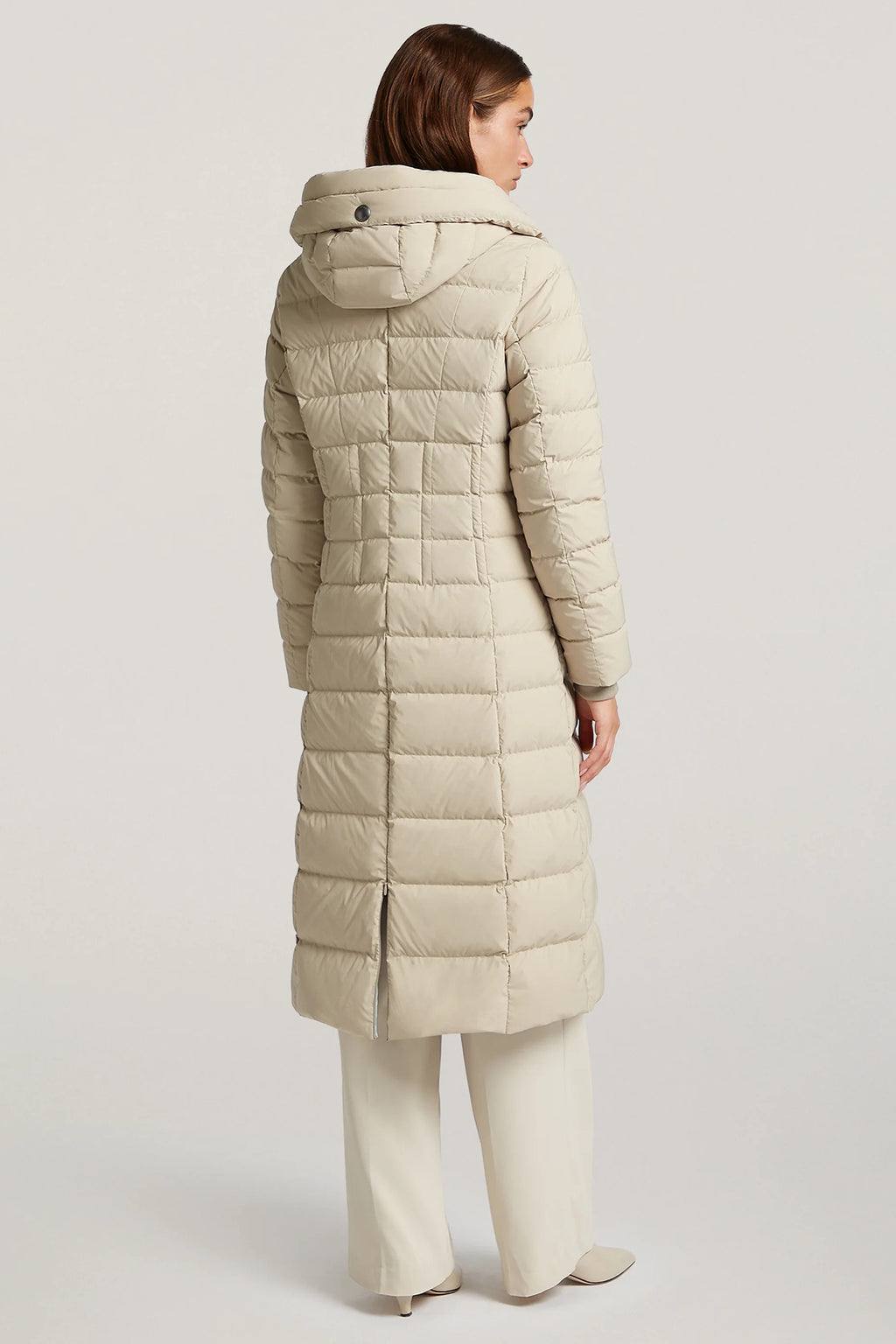 Woman wearing a beige quilted coat on a light gray background