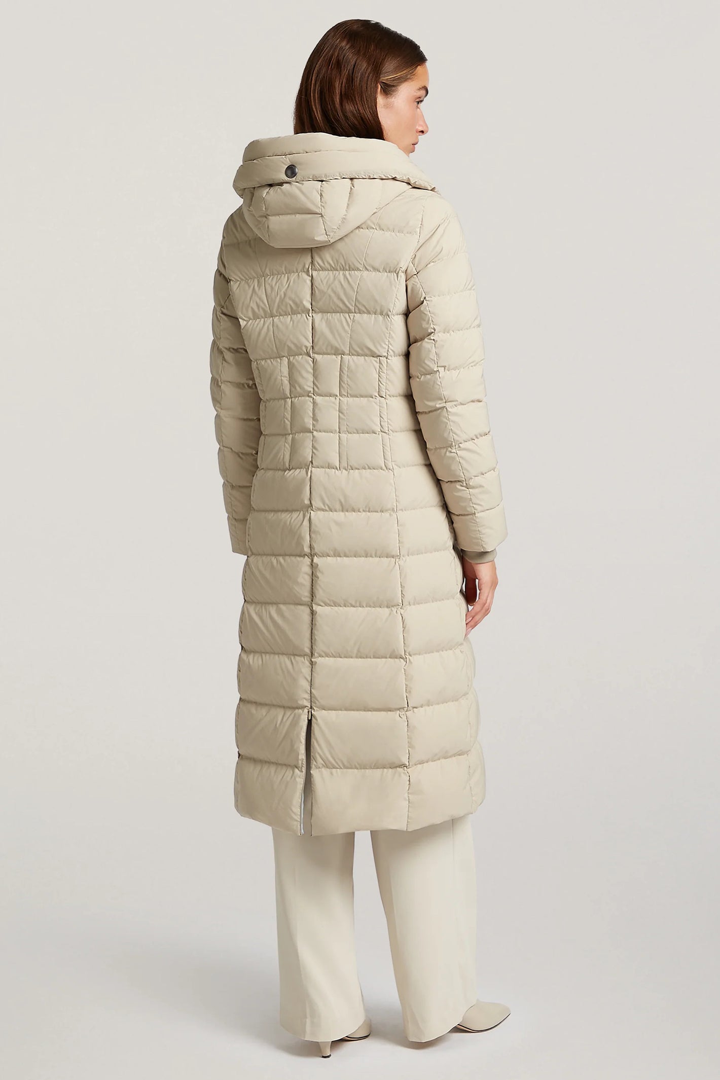 Woman wearing a beige quilted coat on a light gray background