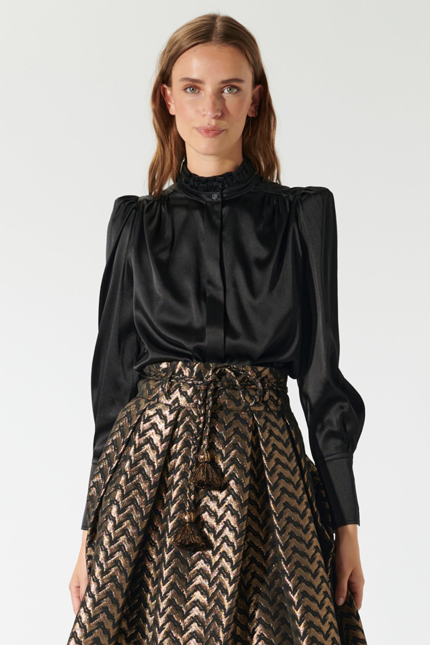 Woman wearing a black blouse and patterned skirt on a white background