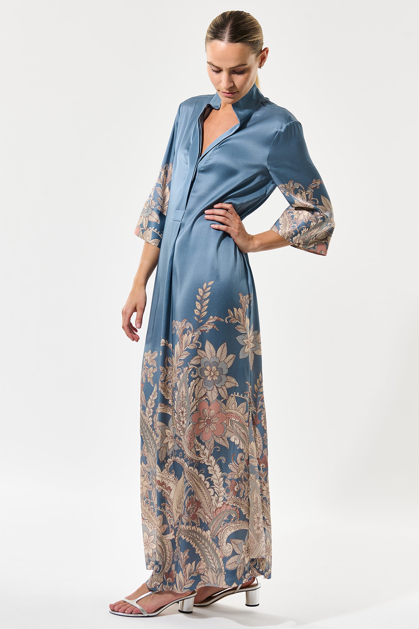 Woman wearing a long, patterned dress with floral designs on a white background