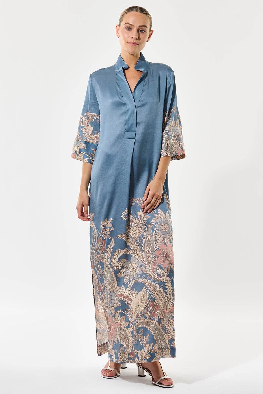 Woman wearing a blue dress with floral patterns on sleeves and hem against a white background
