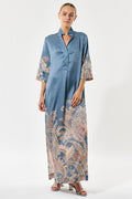 Woman wearing a blue dress with floral patterns on sleeves and hem against a white background