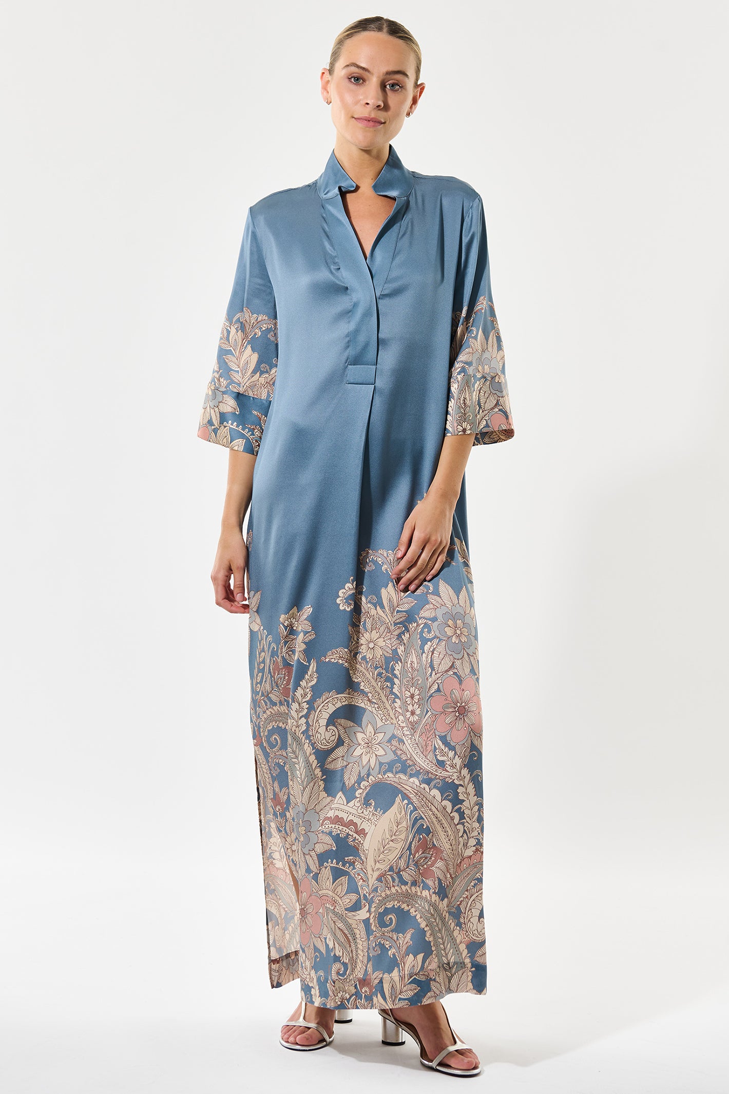 Woman wearing a blue dress with floral patterns on sleeves and hem against a white background