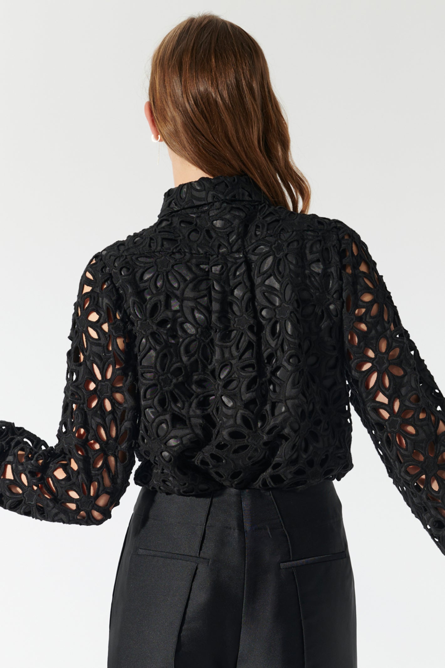 Black lace top worn by a person on a white background