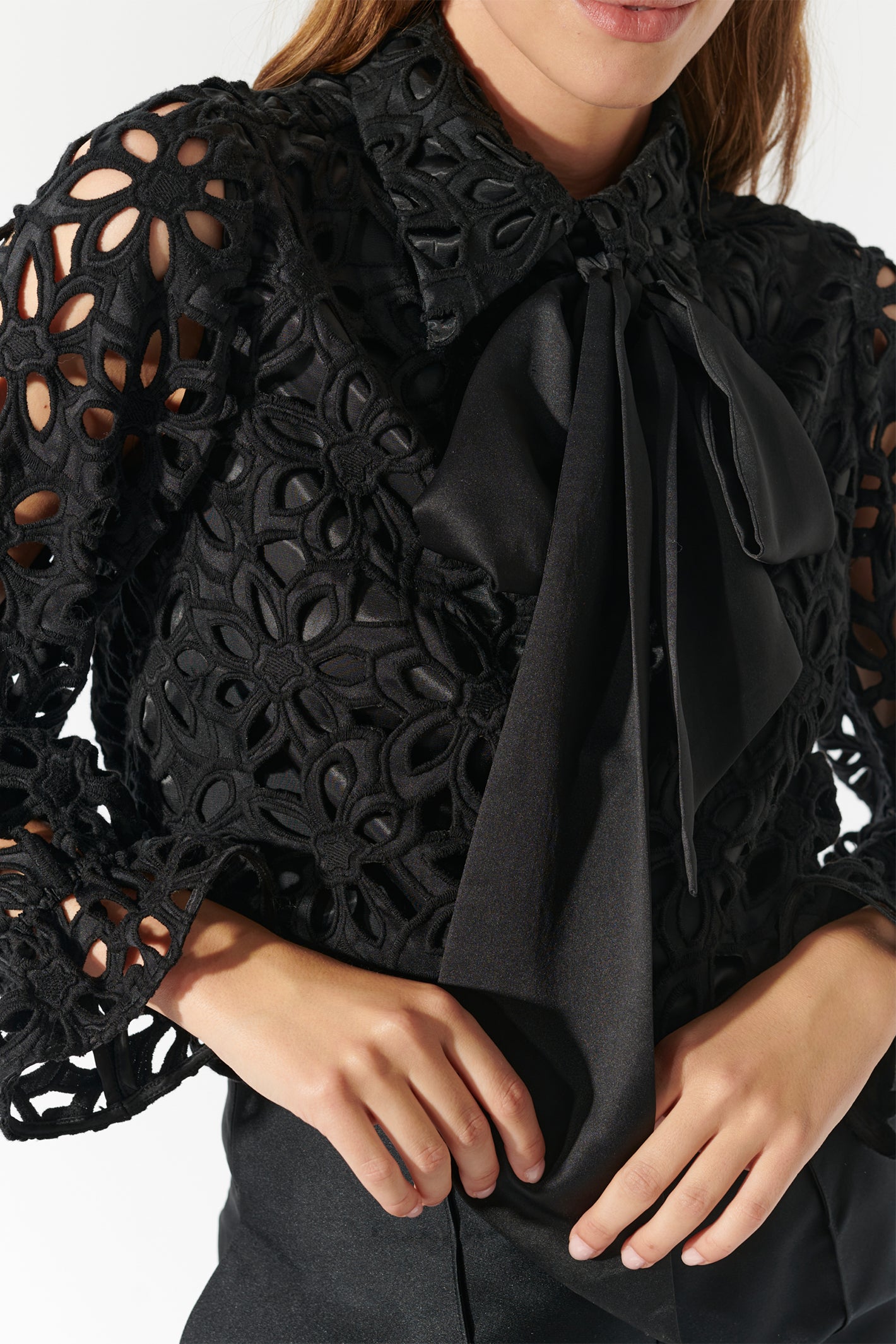 Black lace top with a bow tie worn by a person on a white background