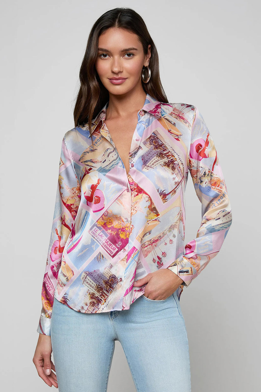 Woman wearing a colorful patterned blouse with light blue jeans on a gray background
