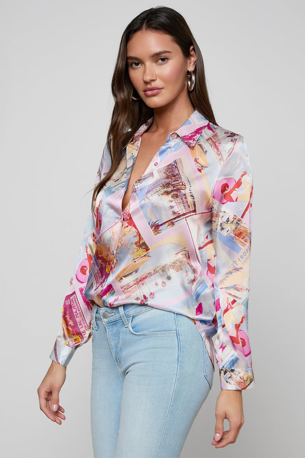 Woman wearing a colorful patterned blouse and light blue jeans on a gray background