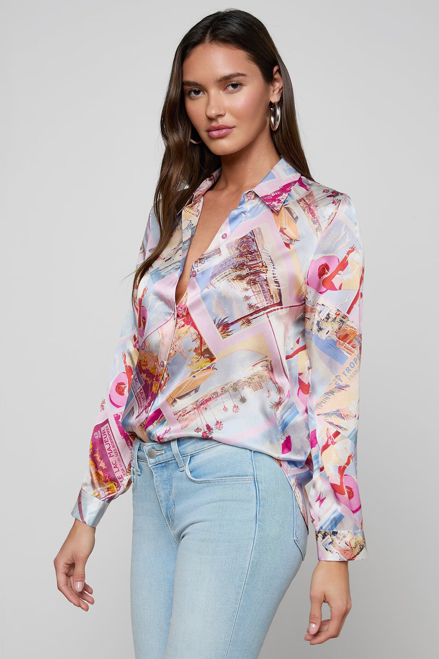 Woman wearing a colorful patterned blouse and light blue jeans on a gray background