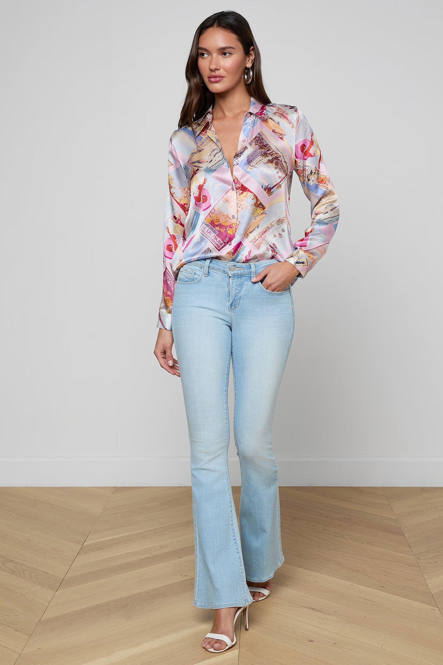 Woman wearing a floral blouse and light blue jeans on a plain background