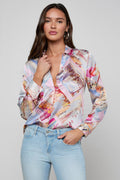 Woman wearing a colorful patterned shirt and light blue jeans on a gray background