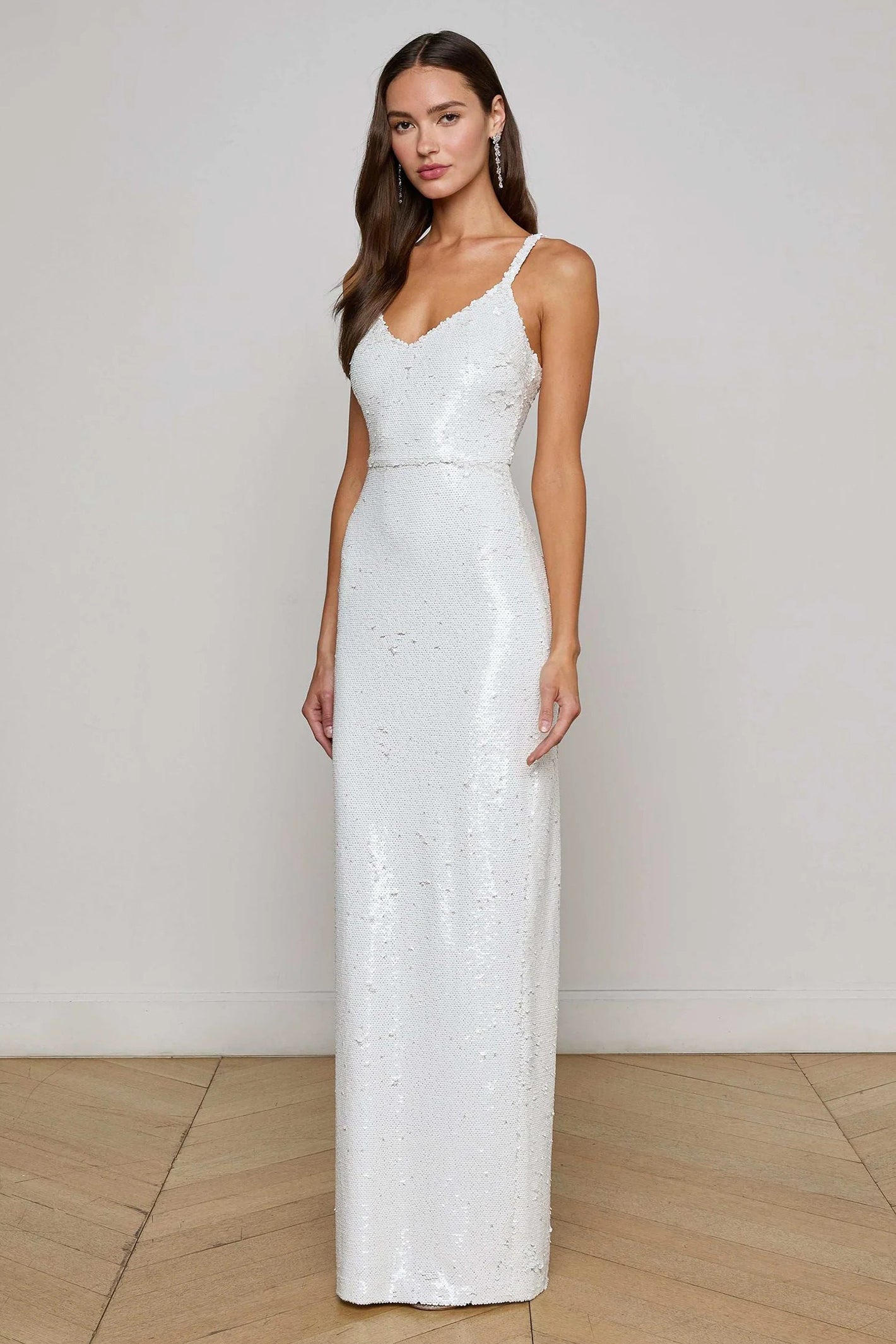 Woman wearing a white sequin gown against a plain background