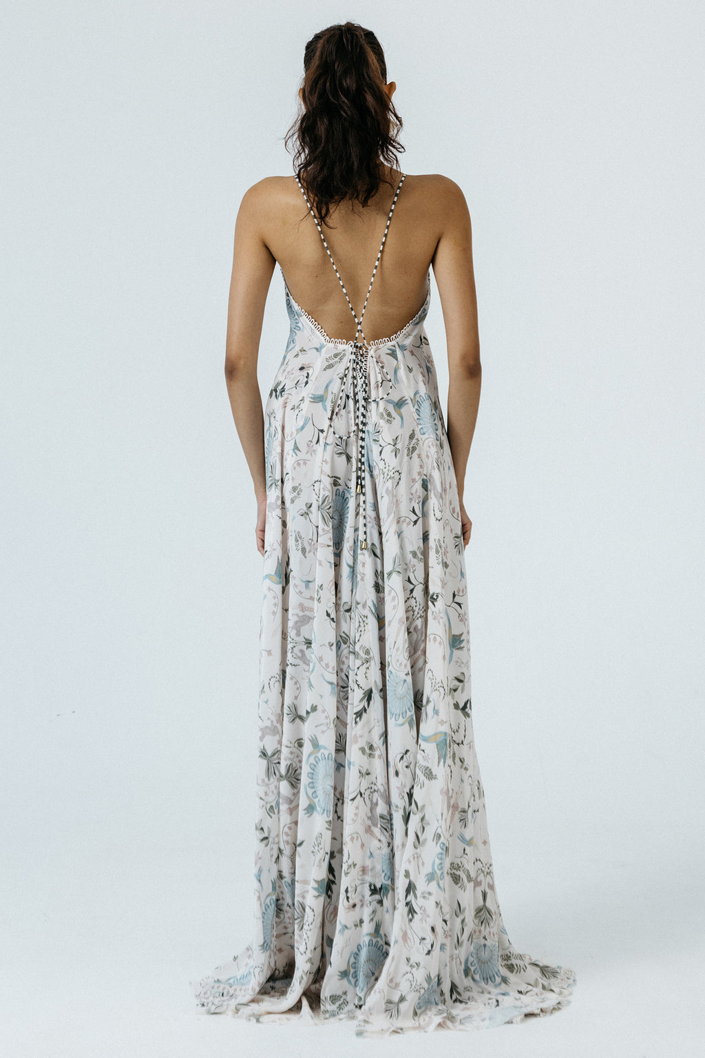 Woman wearing a floral dress with an open back on a white background