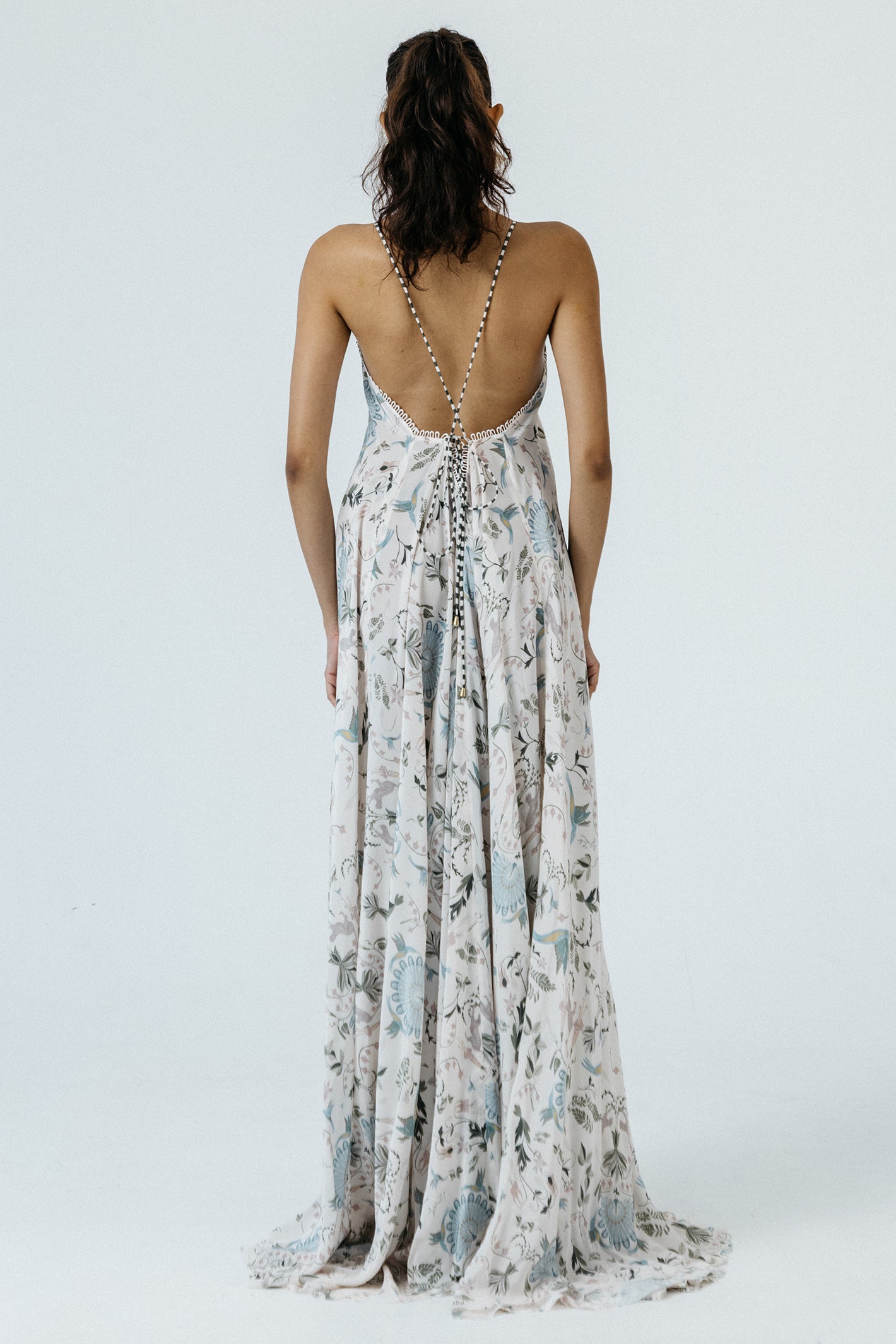 Woman wearing a floral dress with an open back on a white background
