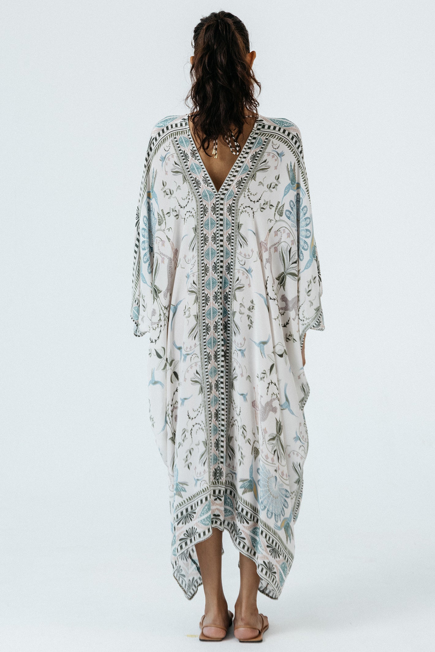 Woman wearing a long, patterned dress on a white background