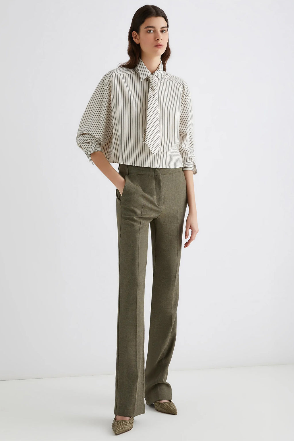 Woman wearing a striped shirt and green pants on a white background