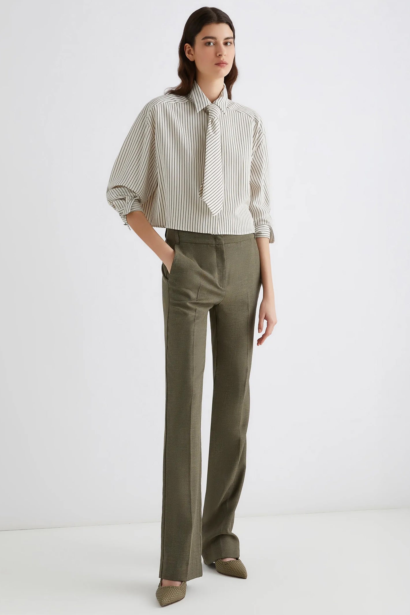 Woman wearing a striped shirt and green pants on a white background