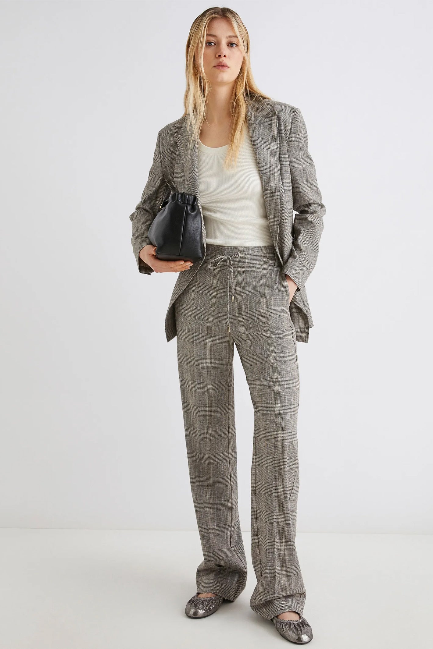 Woman wearing a gray checkered suit with a white top on a white background