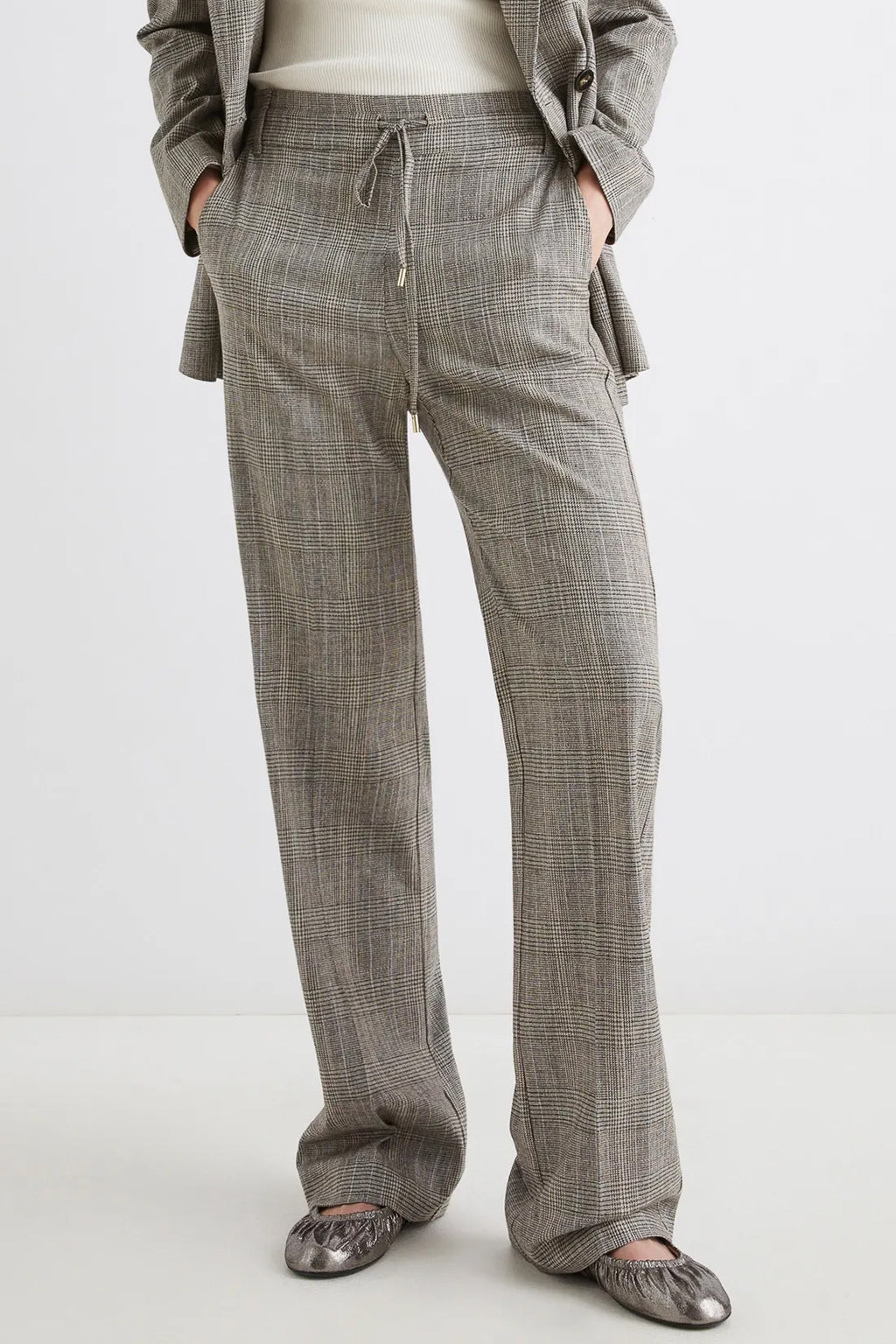 Person wearing gray checkered pants on a white background