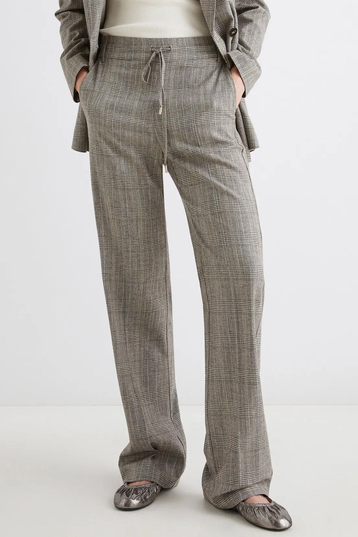 Person wearing gray checkered pants on a white background