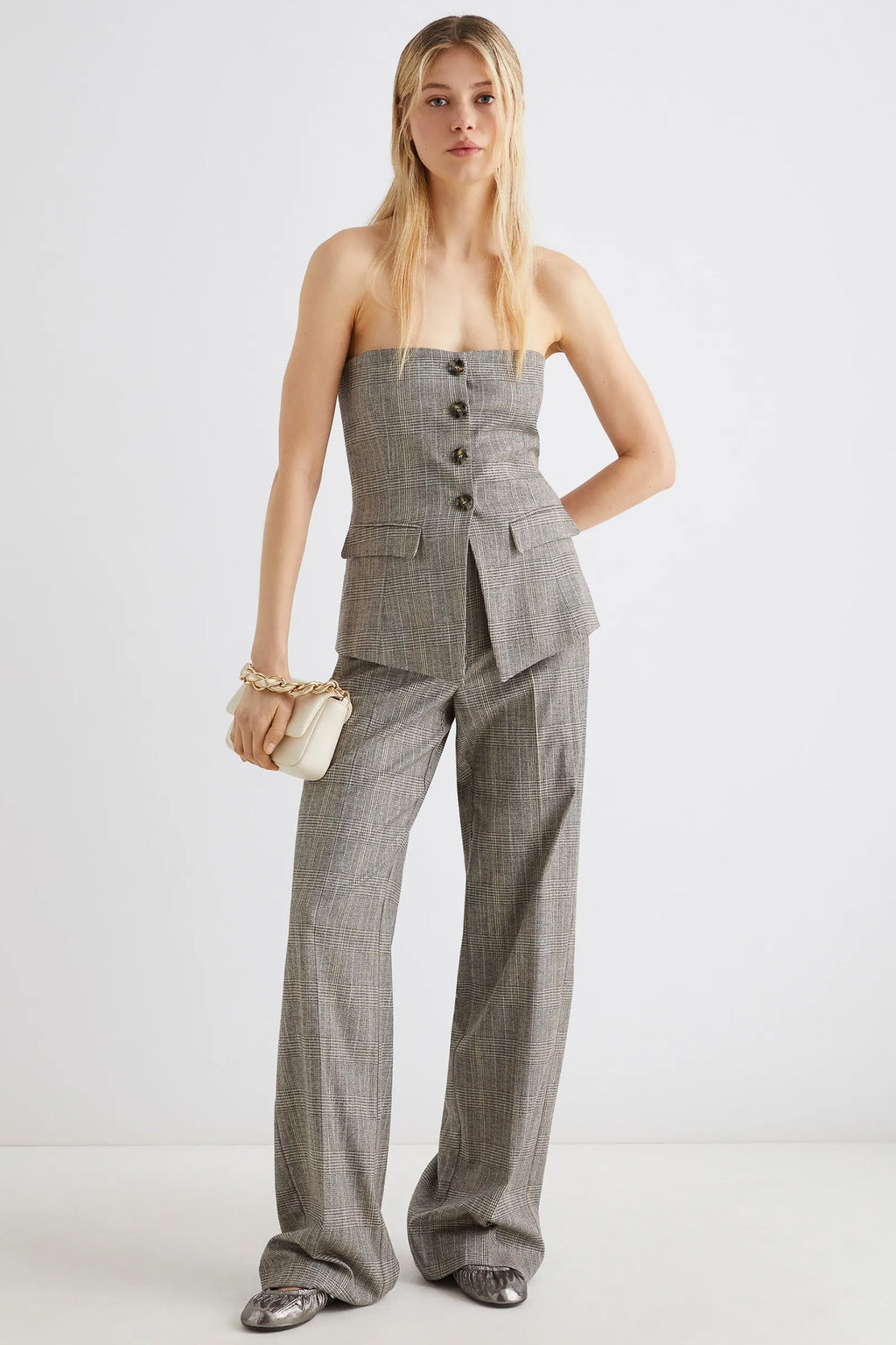Woman wearing a gray suit with wide-leg pants on a white background