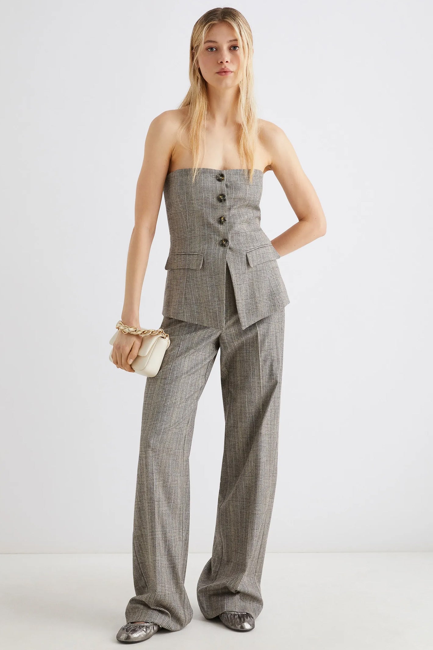 Woman wearing a gray suit with wide-leg pants on a white background
