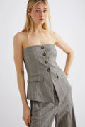 Woman wearing a gray strapless blazer and wide-leg pants on a white background