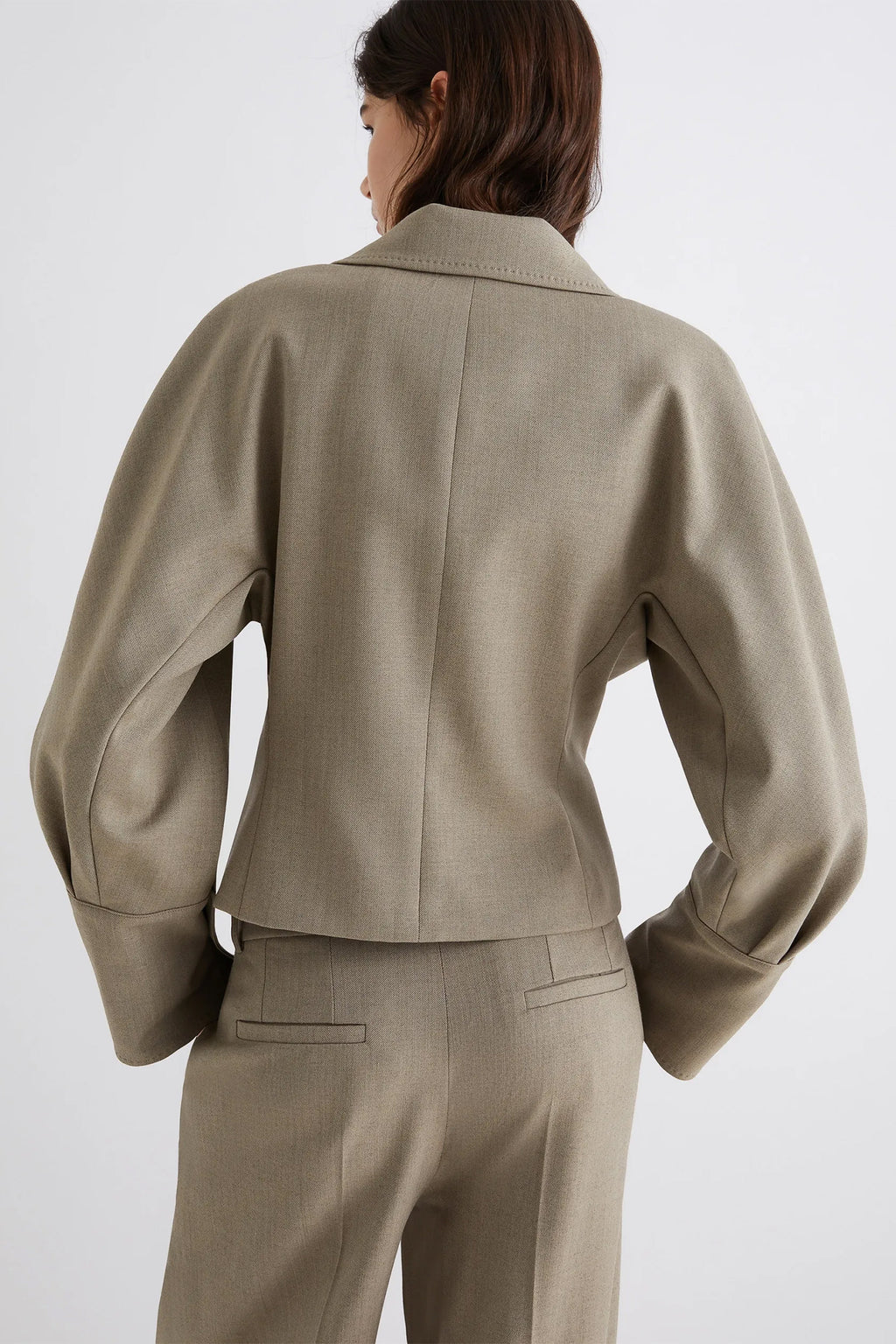 Person wearing a beige suit on a white background