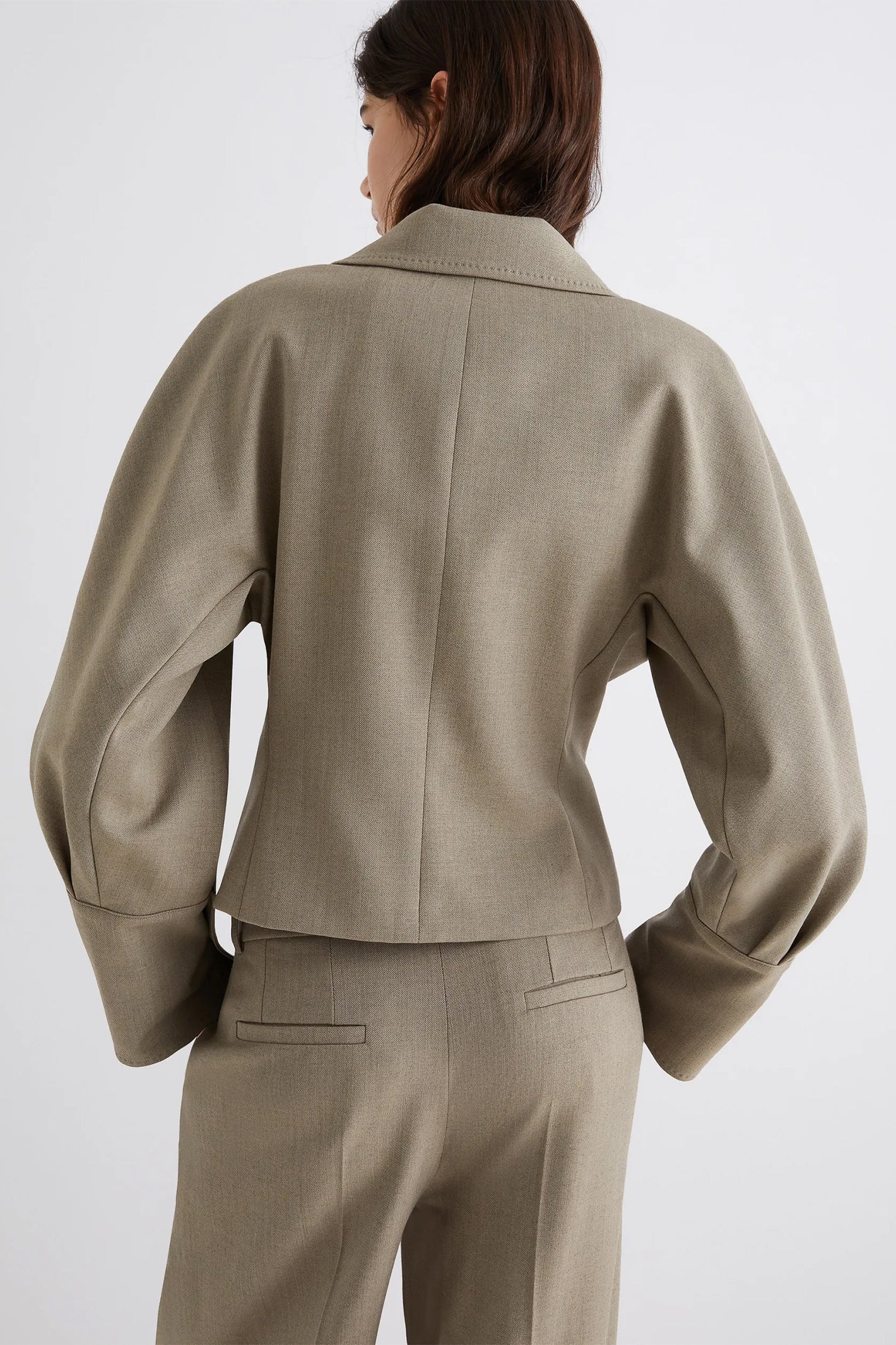 Person wearing a beige suit on a white background