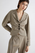 Woman wearing a beige suit with a plain background