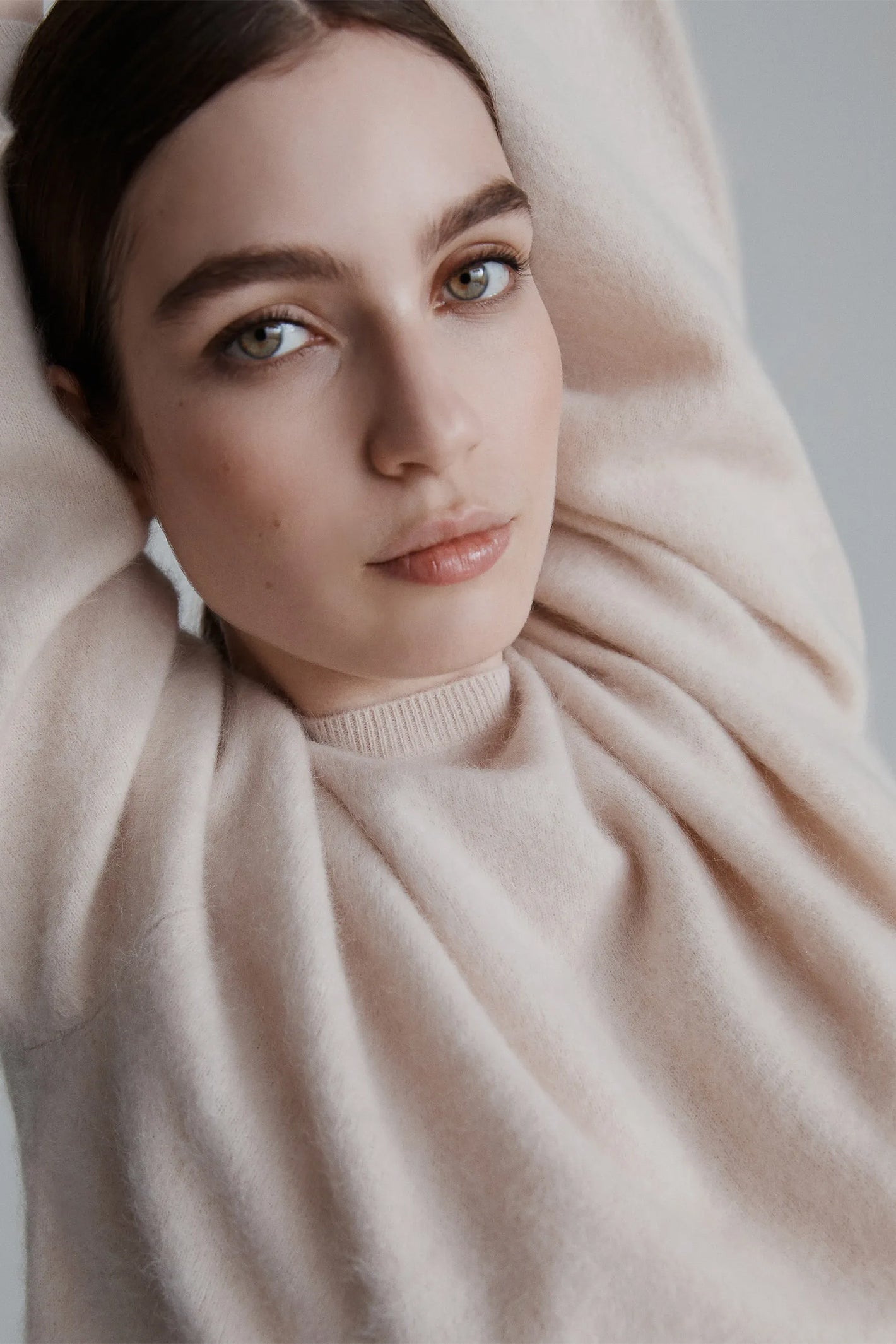 Woman wearing a beige sweater with a neutral background
