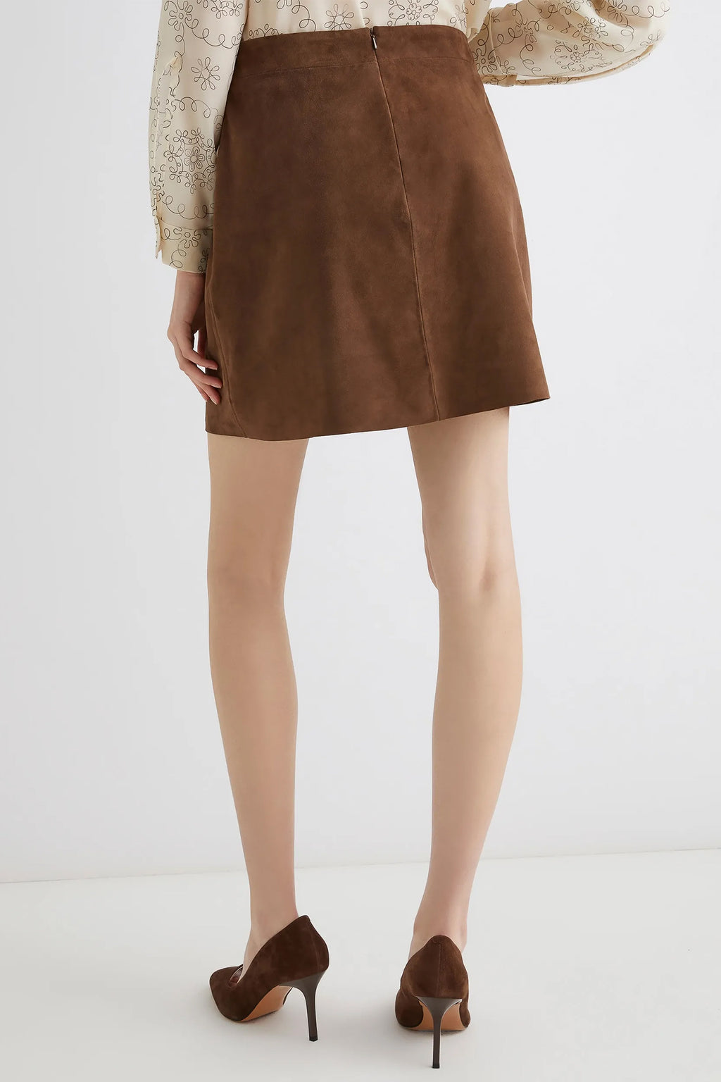 Brown suede skirt worn by a person on a white background
