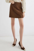 Person wearing a brown skirt and matching shoes on a white background