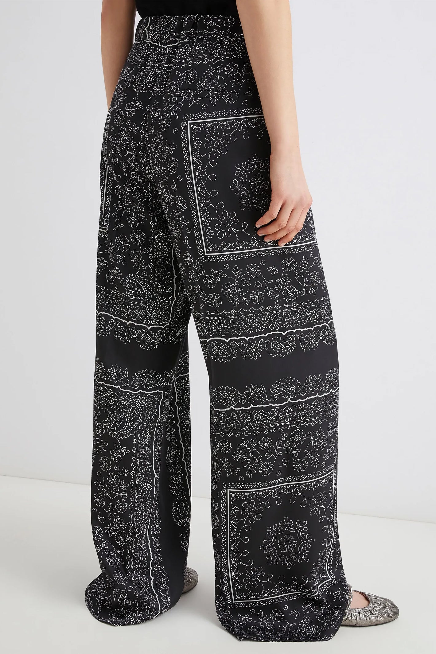 Black patterned wide-leg pants worn by a person on a white background