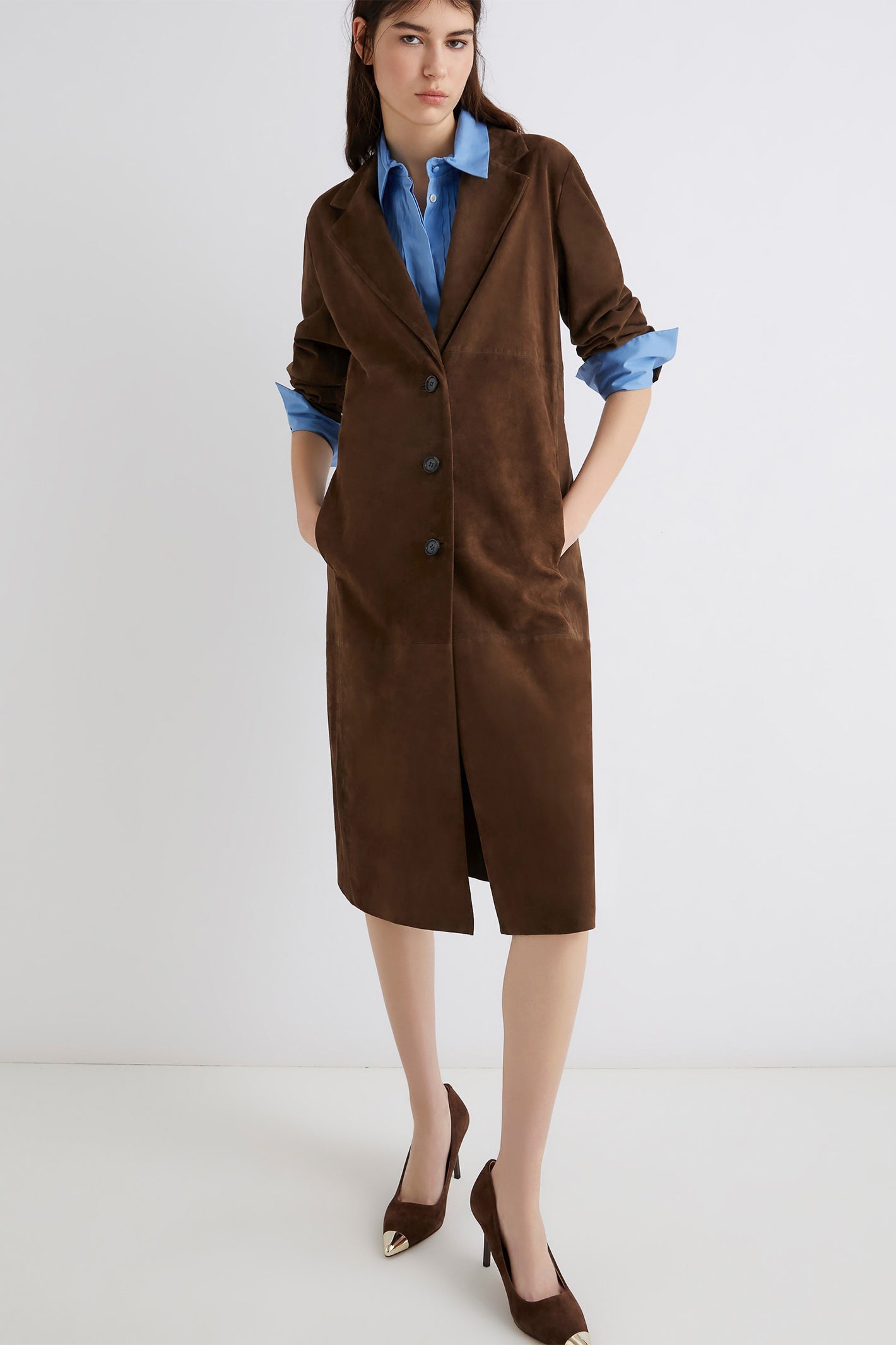 Woman wearing a brown coat over a blue shirt on a white background