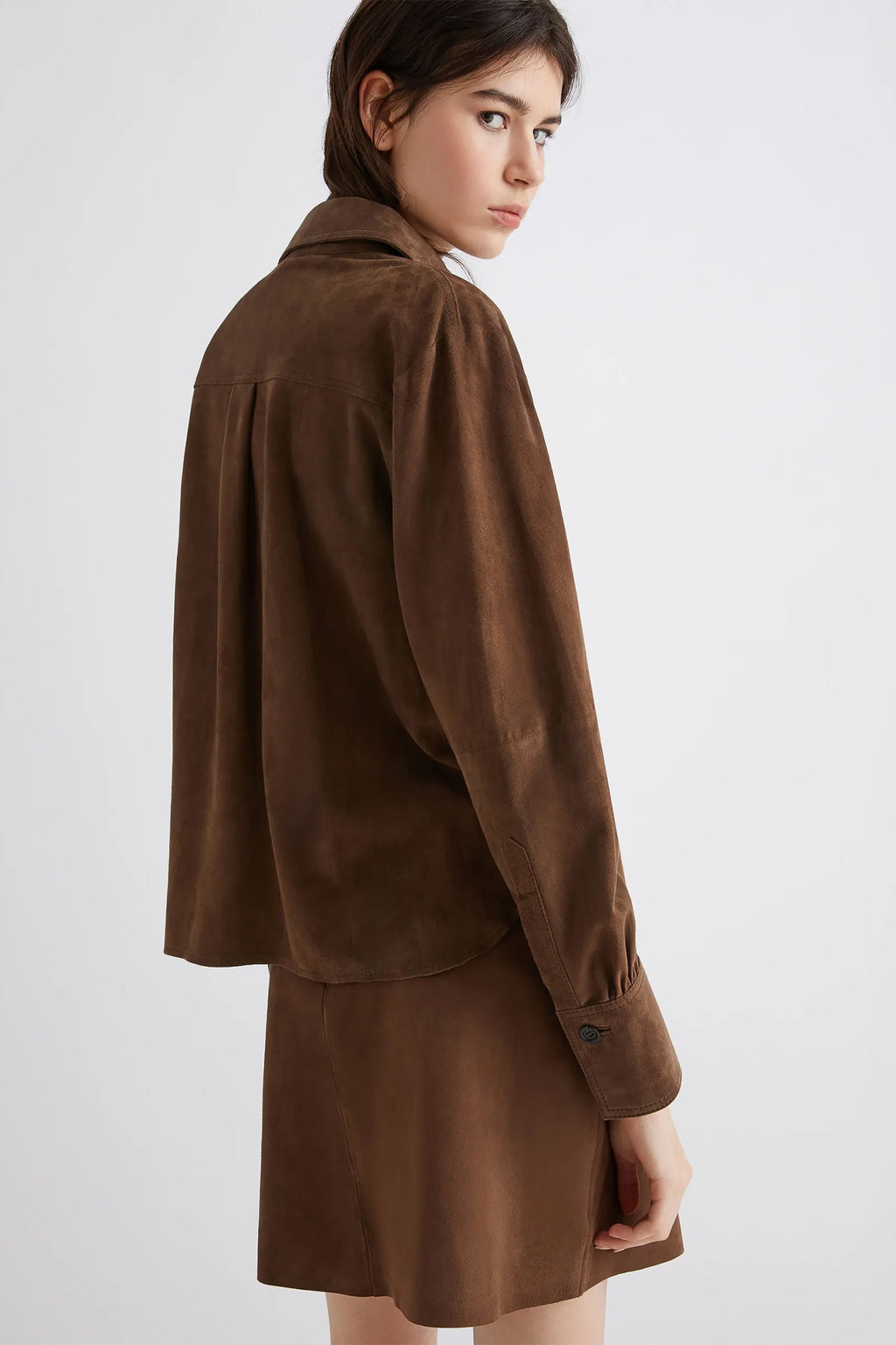 Woman wearing a brown jacket and skirt set on a white background