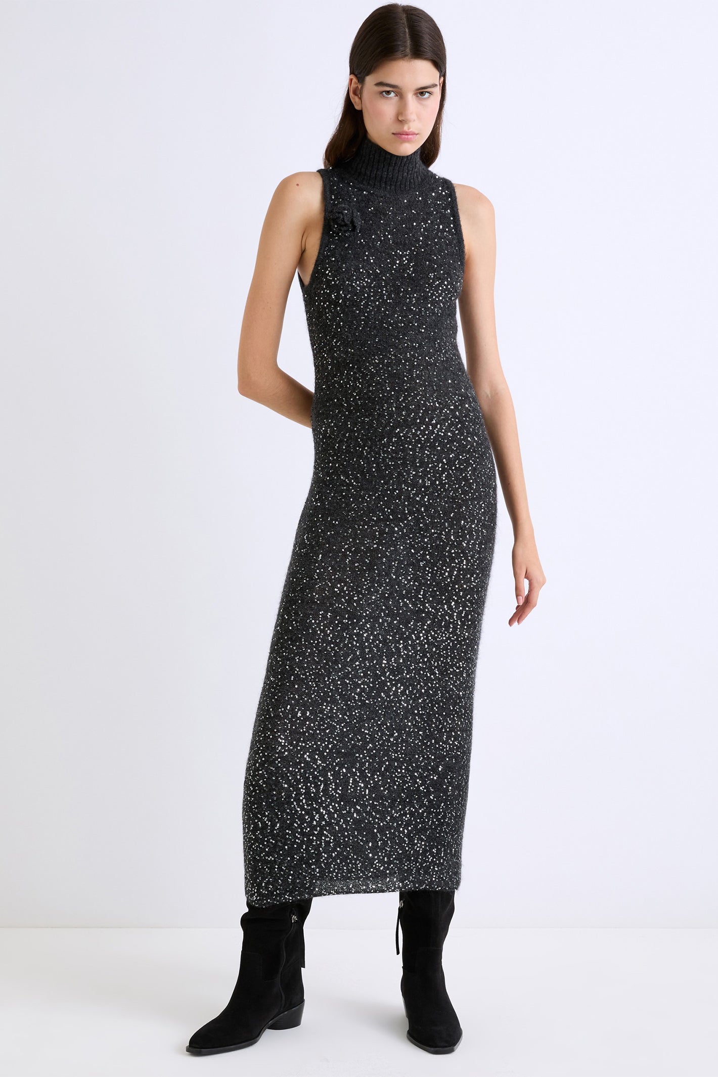 Woman wearing a grey sleeveless dress with a textured pattern on a white background