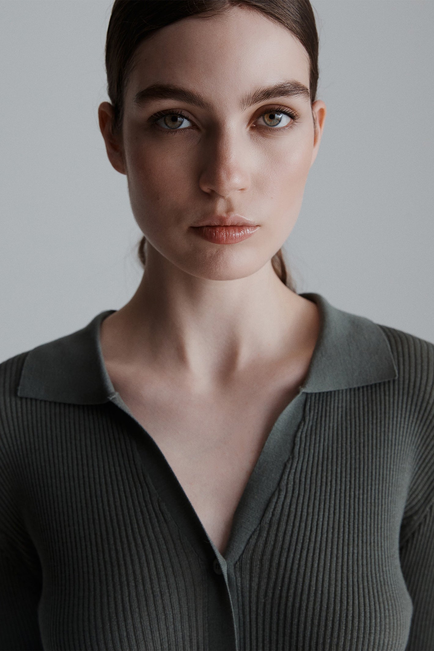 Woman wearing a dark ribbed cardigan against a plain background