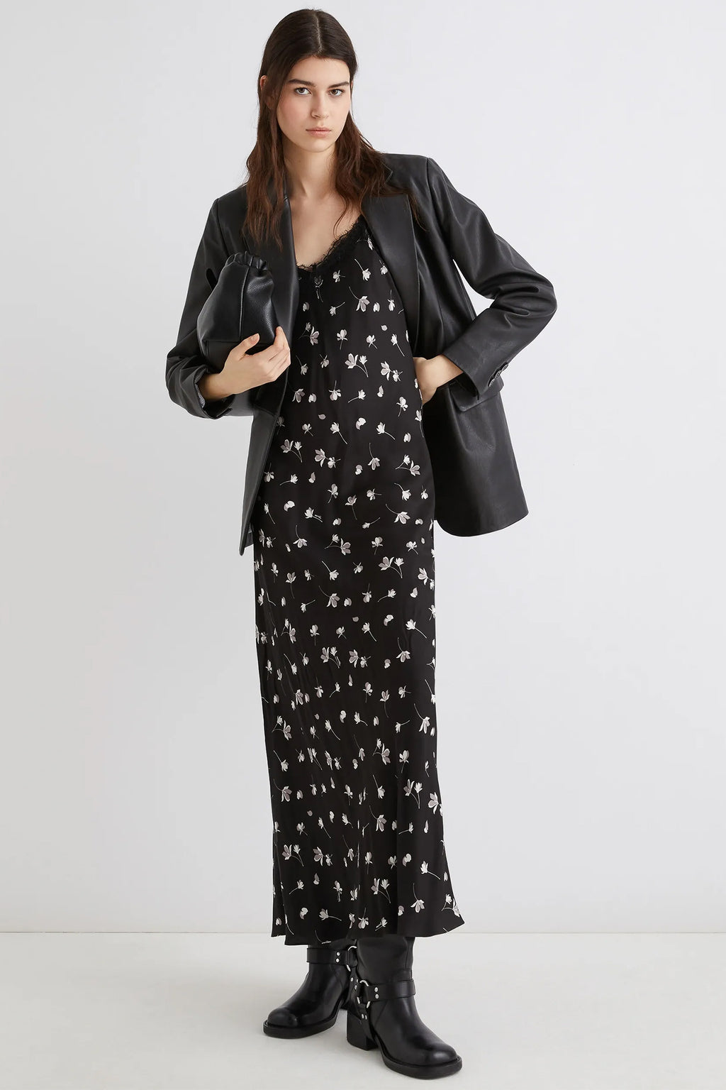Woman wearing a black floral dress with a black leather jacket on a white background
