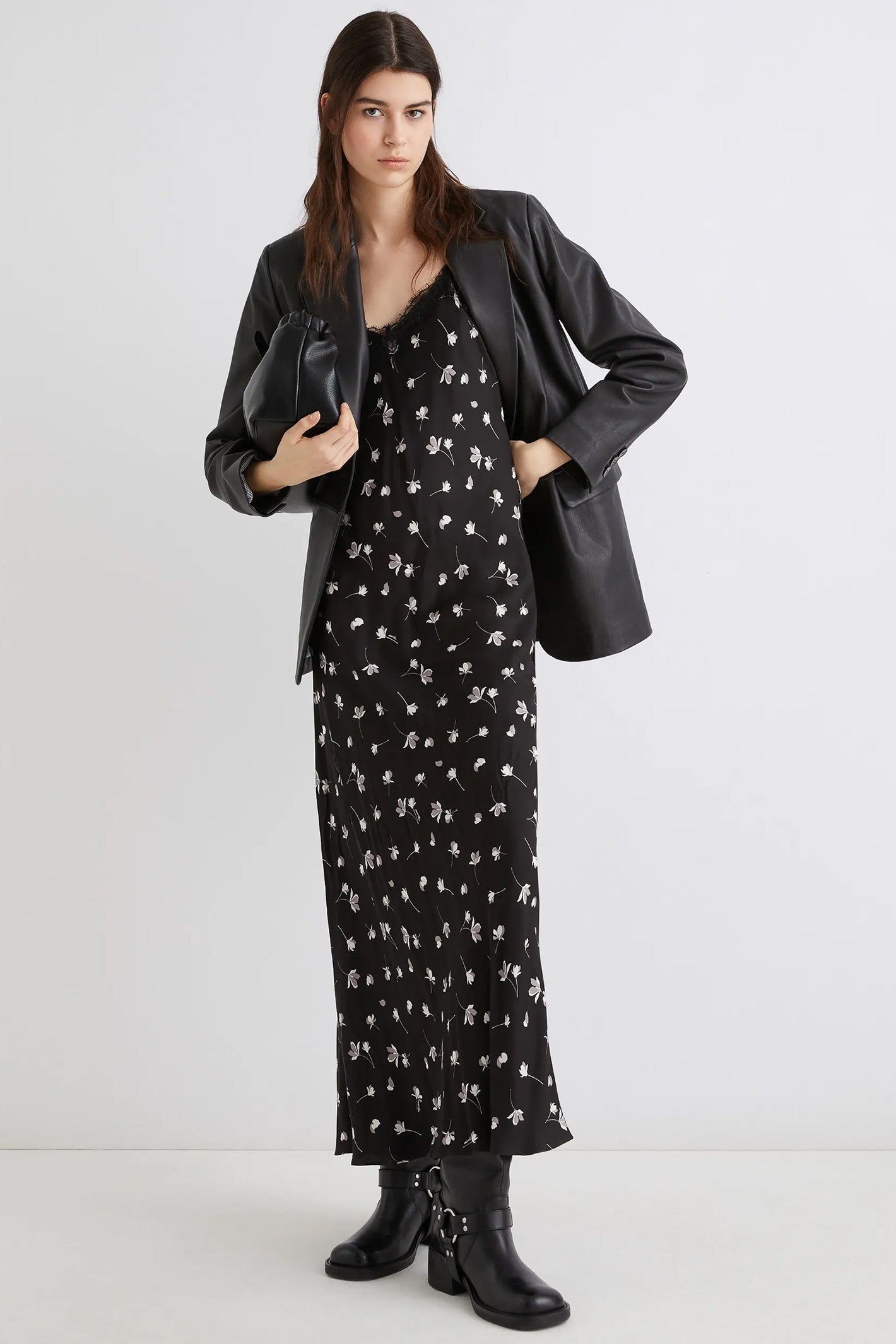 Woman wearing a black floral dress with a black leather jacket on a white background
