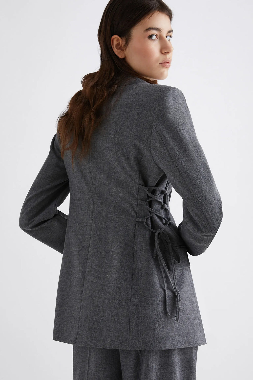 Woman wearing a gray suit with a tie waist on a white background