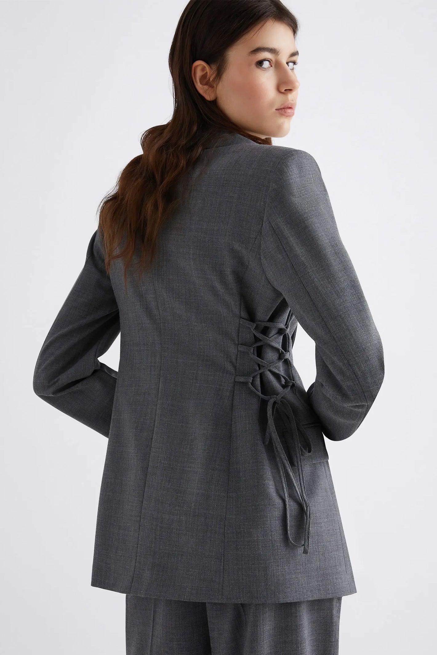 Woman wearing a gray suit with a tie waist on a white background