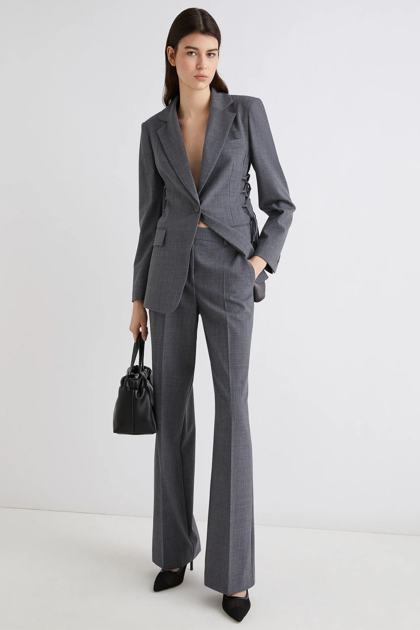 Woman wearing a gray suit with a black handbag on a white background