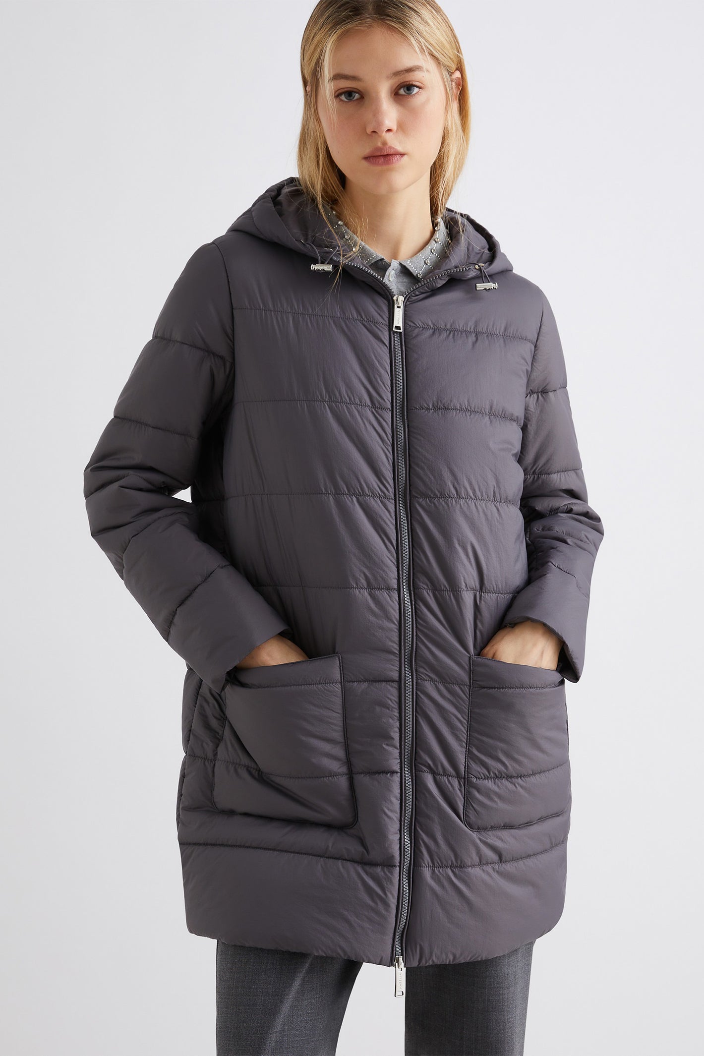Woman wearing a gray quilted jacket on a white background