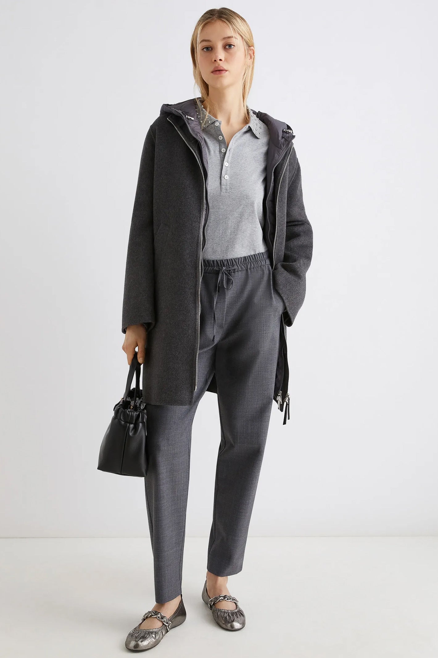 Woman wearing a gray coat and pants with a white background