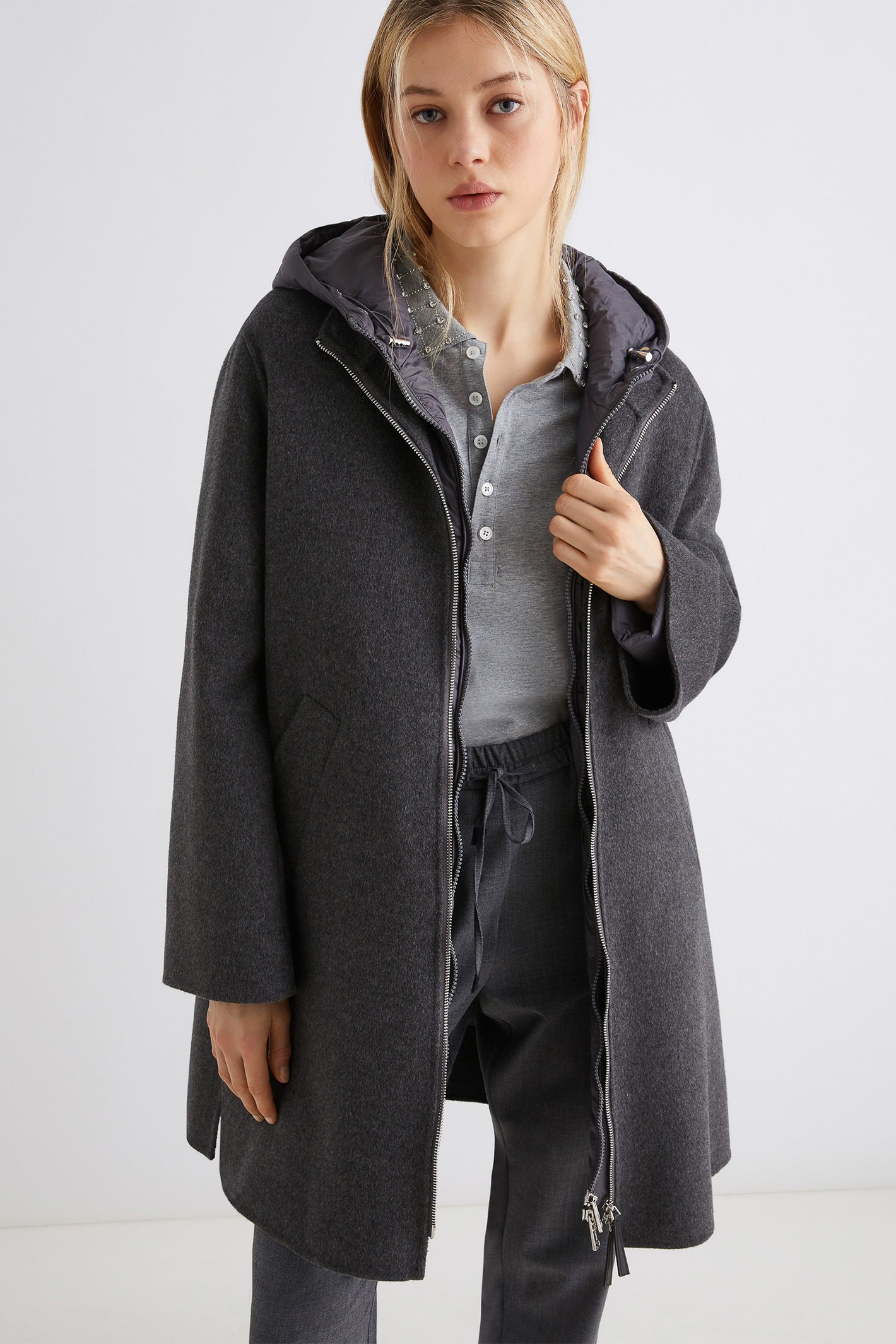 Person wearing a gray coat with a white background