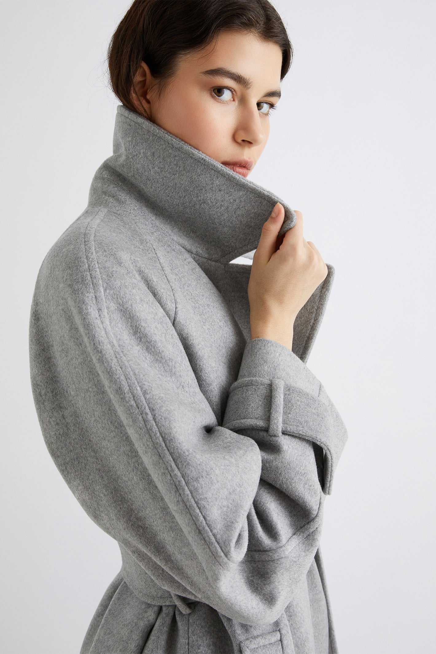 Woman wearing a gray coat on a light gray background