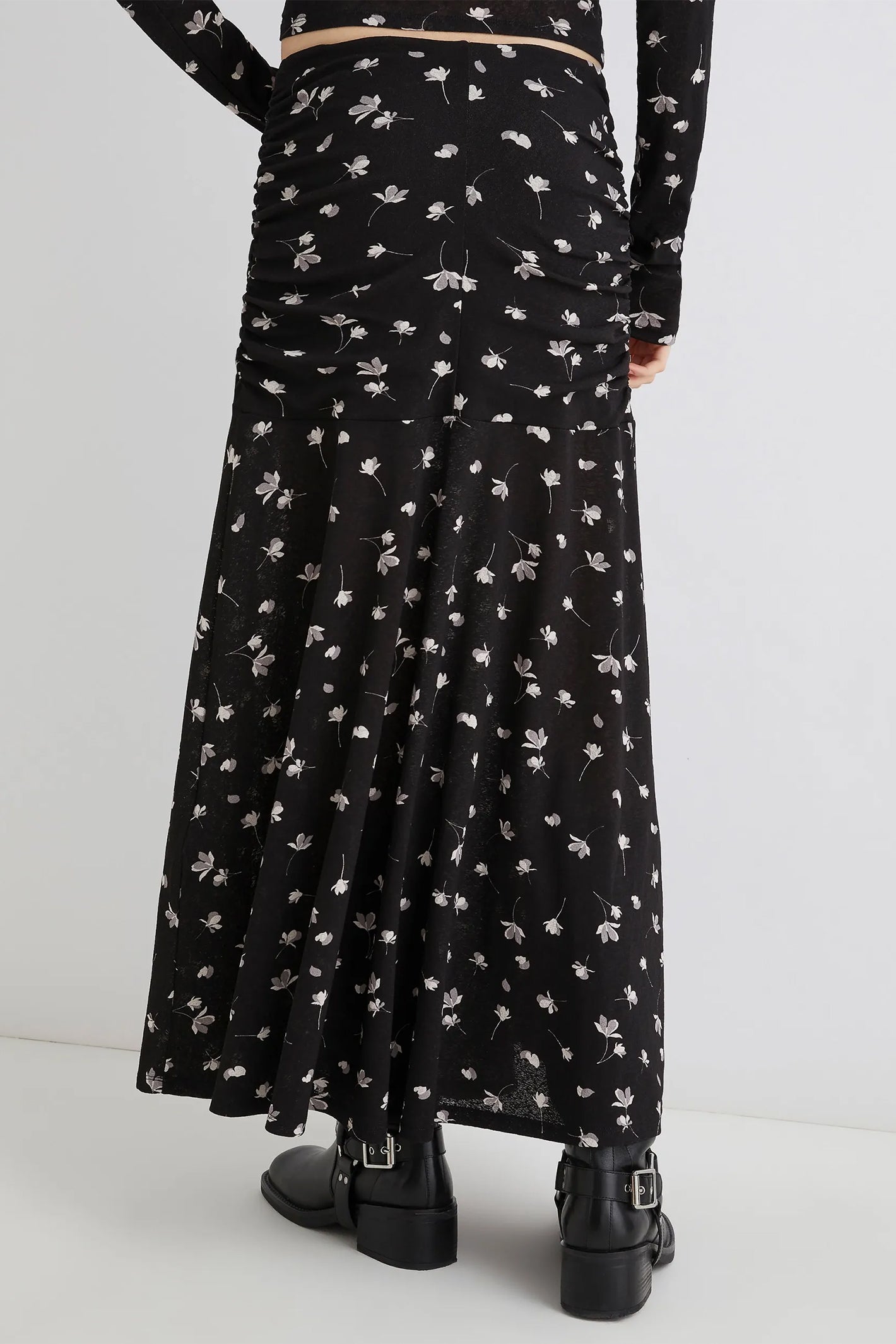 Black floral-patterned dress worn by a person on a white background