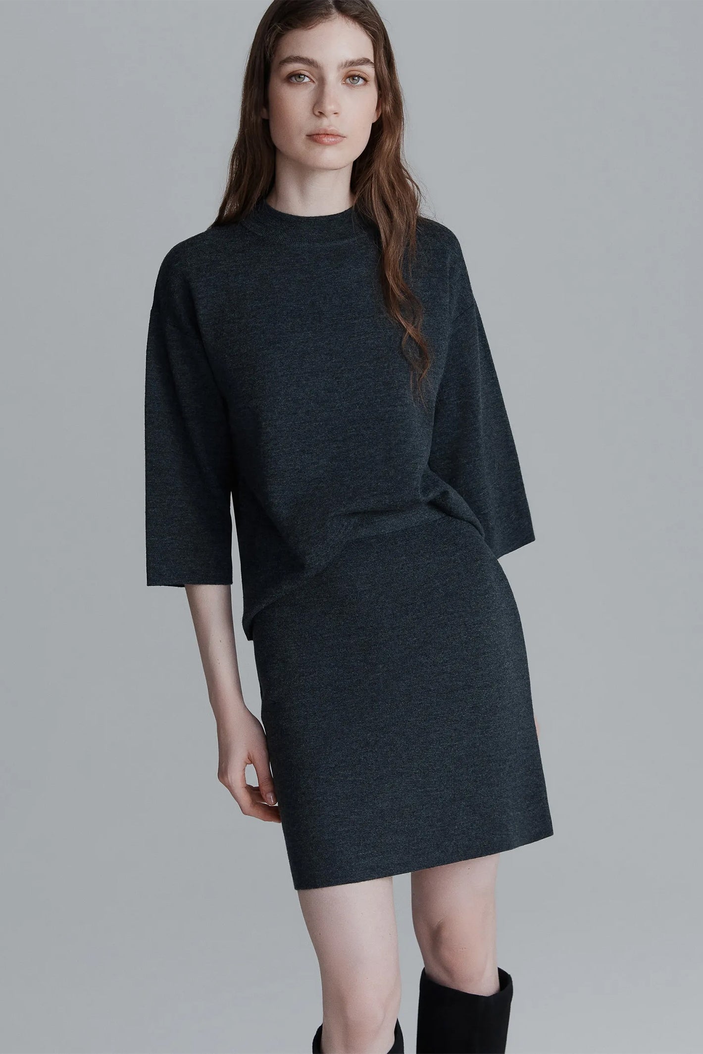 Woman wearing a dark gray dress against a plain background