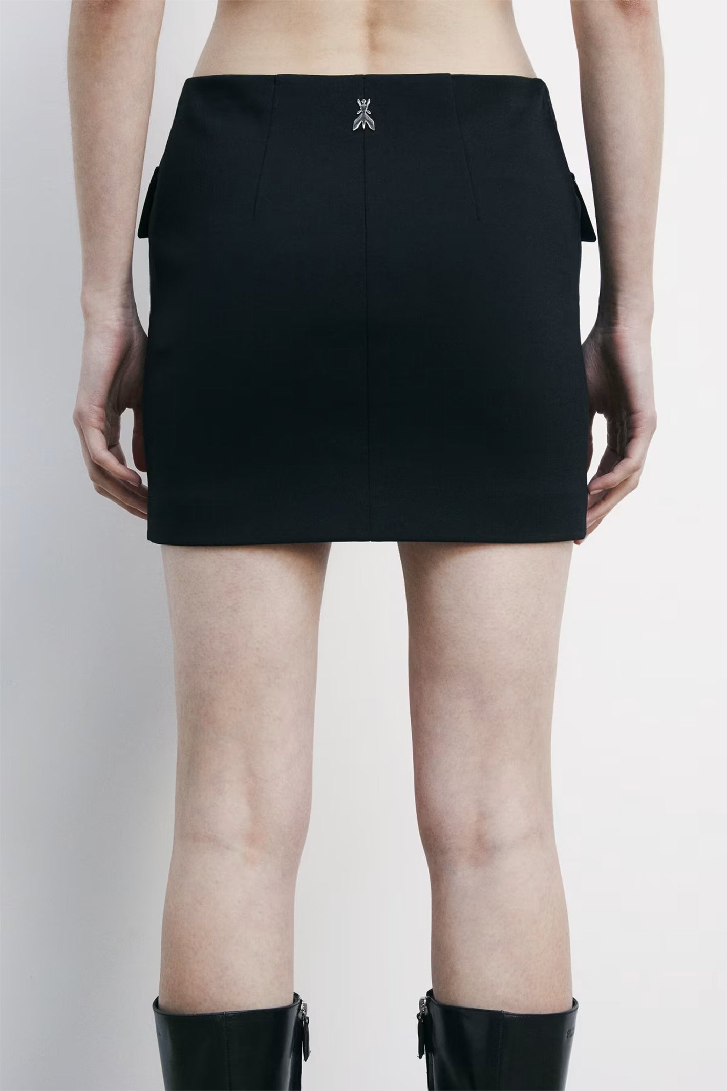 Person wearing a black skirt on a plain background