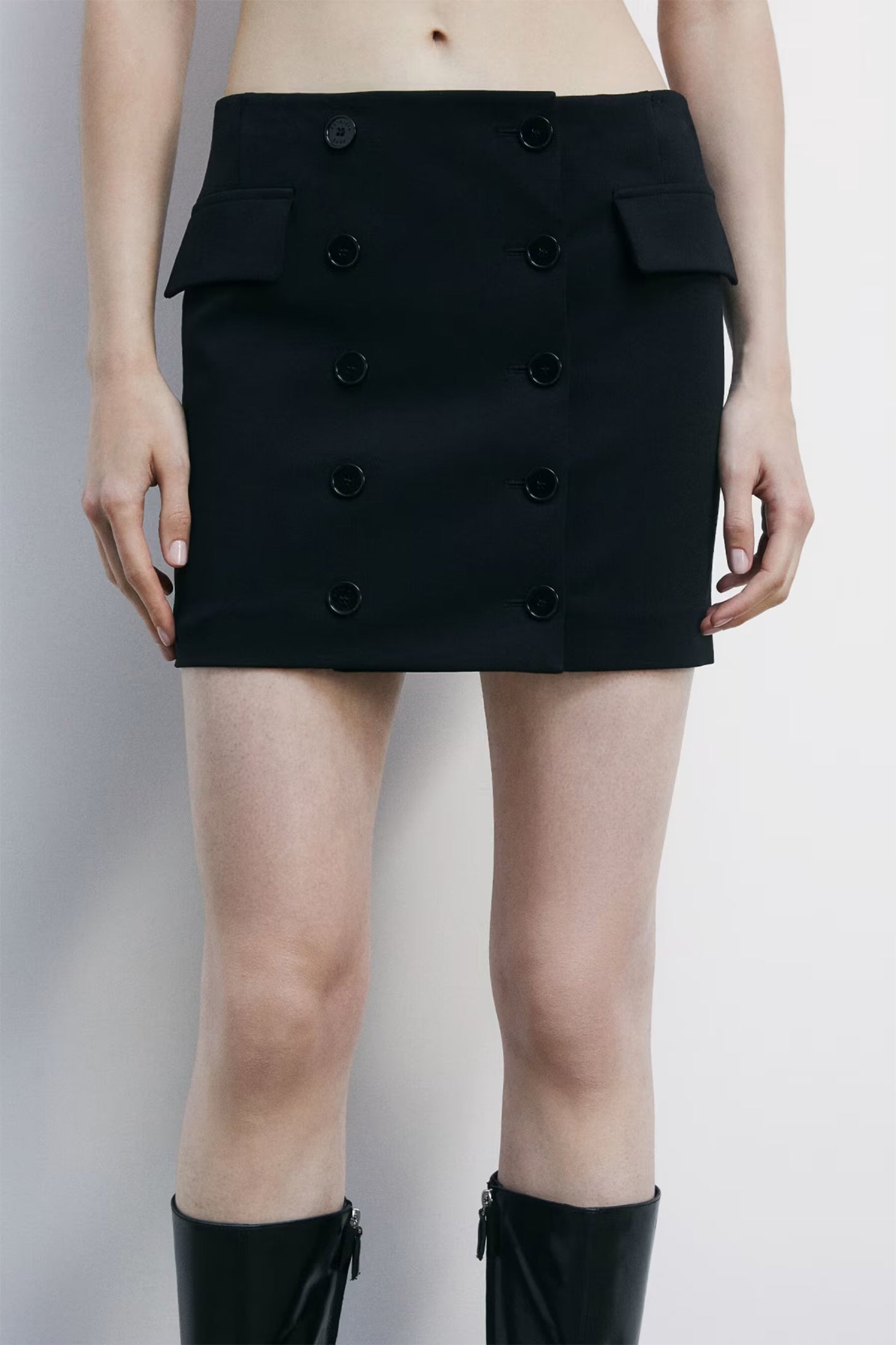 Black skirt with button details worn by a person on a plain background